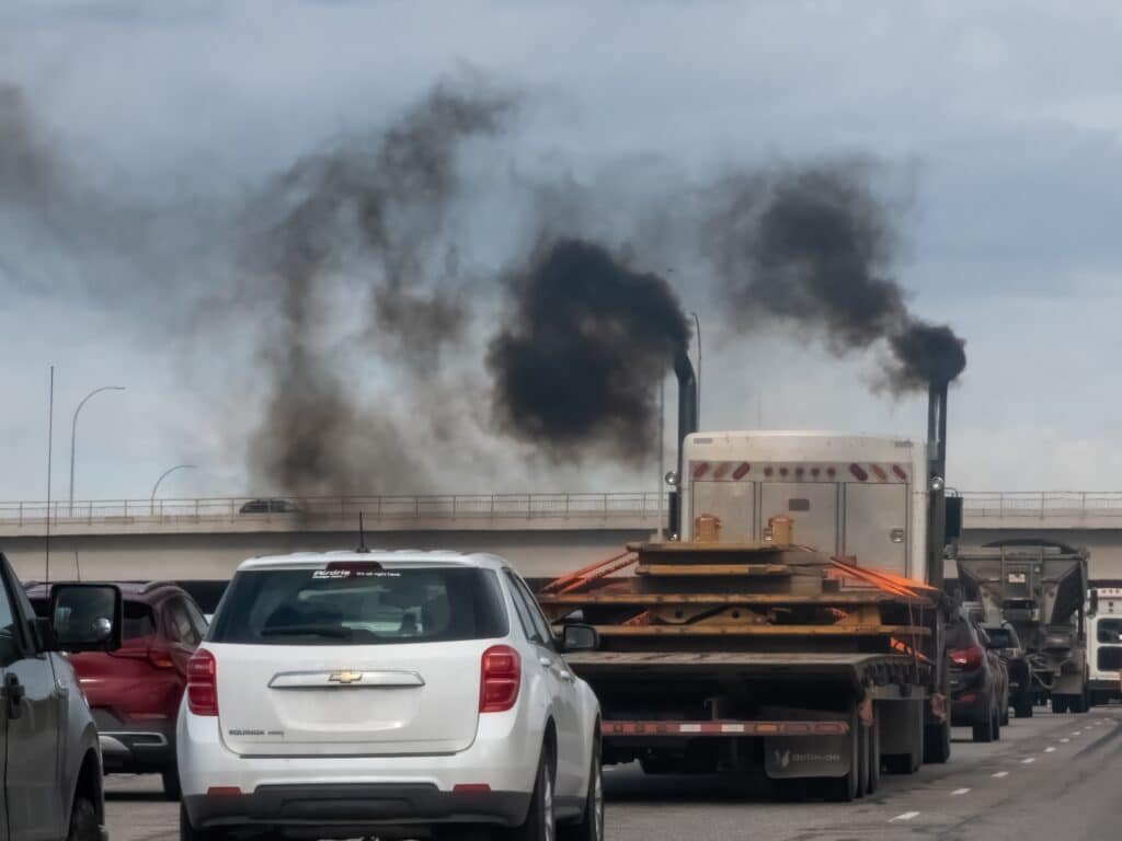 Heavy traffic on a highway with a truck emitting thick black smoke from its exhaust stacks, causing air pollution, Shutterstock ID#2473720255